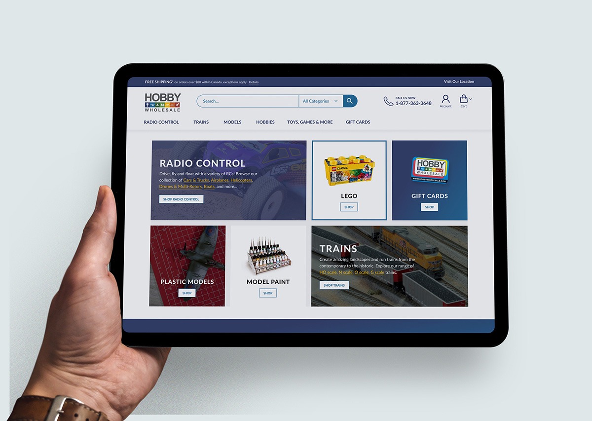 Photo of a person holding a tablet that displays the Hobby Wholesale website homepage