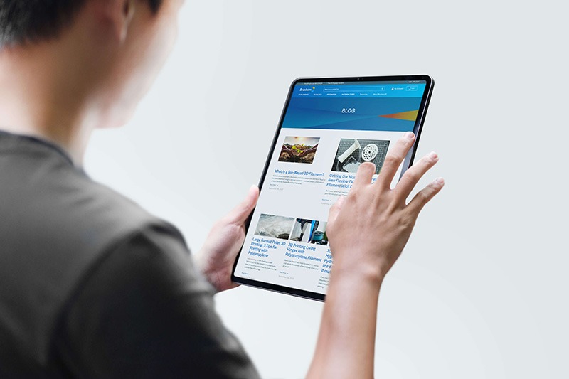 Man holding tablet, screen displays the Braskem3D website blog