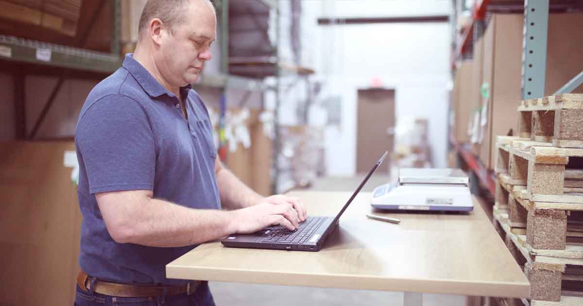 B2B ecommerce manager using laptop in warehouse to manage orders and inventory on Shopify